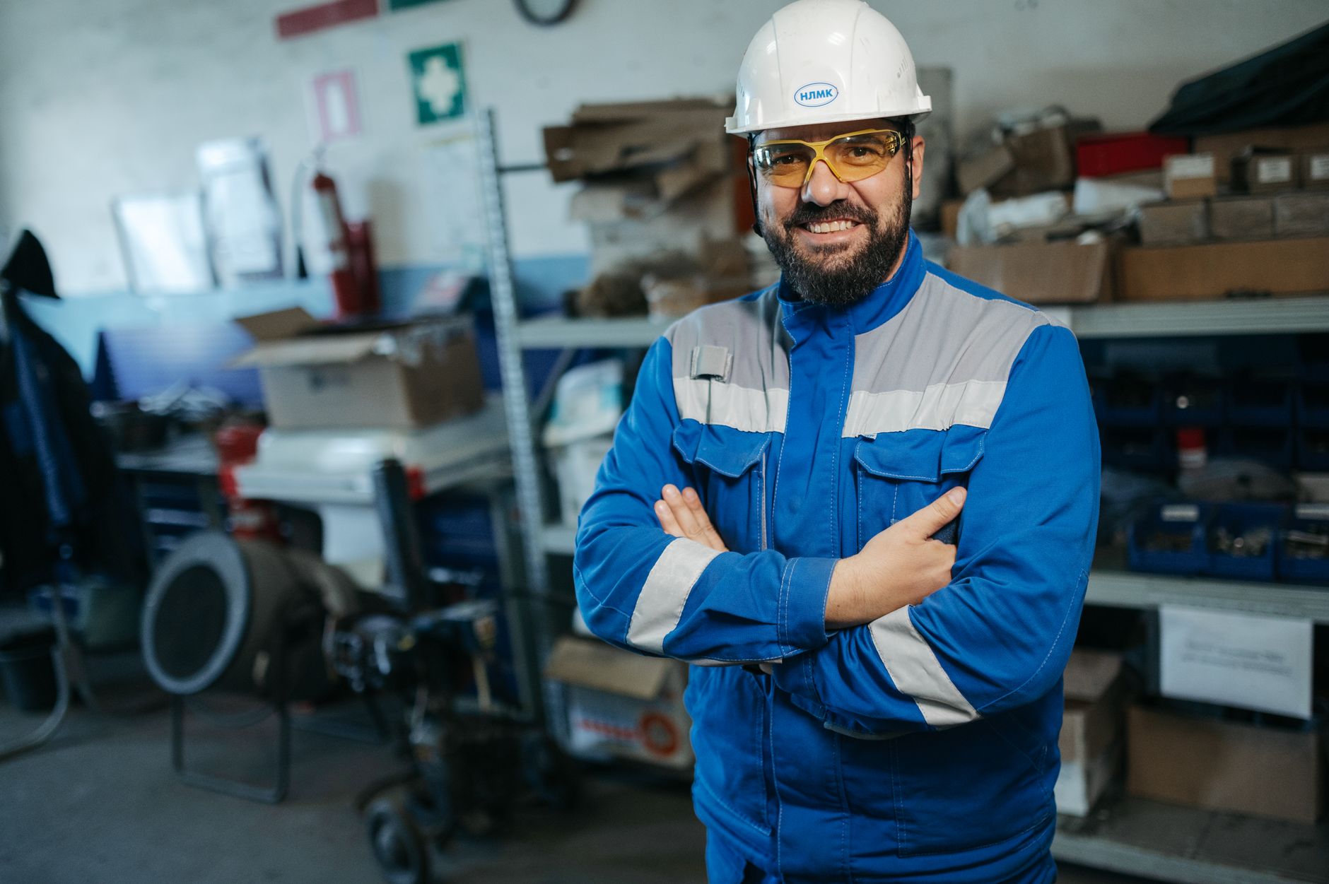 Smiling worker in blue uniform and hard hat standing in a factory setting in Russia.