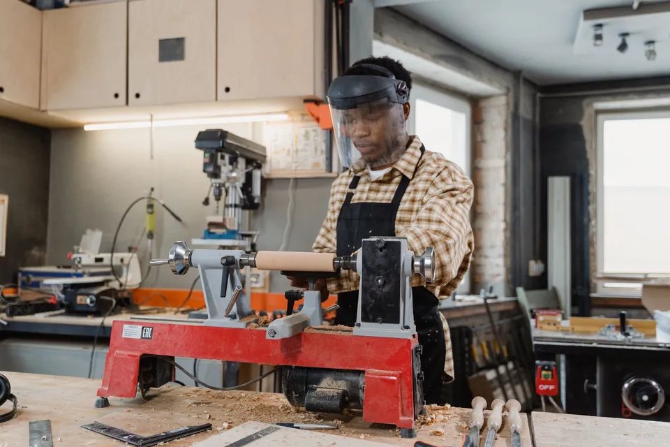 A professional craftsman skillfully works on a project using a lathe in a woodworking workshop.