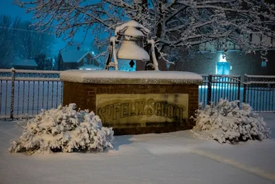 A serene night view of a snow-covered school entrance in Wabasha, Minnesota under soft blue lighting.